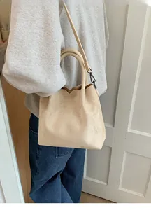 Détail du sac seau en daim beige avec bandoulière réglable et texture douce au toucher