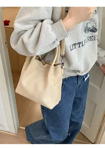 Détail du sac à bandoulière en daim beige avec bord ondulé et sangle amovible