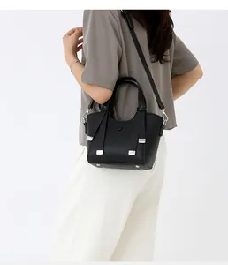 Détail d'un sac à main en cuir grainé noir avec ferrures argentées et bandoulière amovible