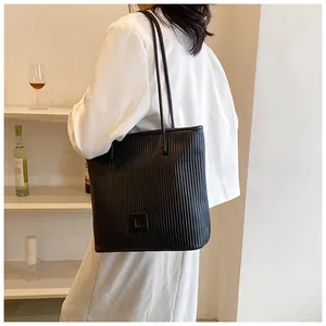Detailed view of the vertical pleated texture and square logo on black tote bag