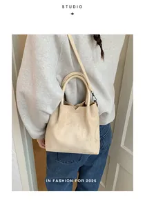 Détail du sac seau en daim beige avec bord ondulé et bandoulière réglable