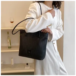 Detail of vertical pleated texture on a black faux leather tote bag with shoulder straps