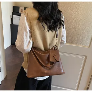 Dettaglio della borsa tote in pelle marrone con pochette coordinata e il logo