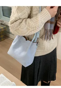 Détail du sac seau en daim bleu clair avec pull en maille d'hiver et écharpe