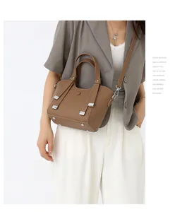 Sac à main marron en cuir grainé avec détails argentés porté par un modèle