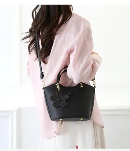 Black pebble leather bucket bag with gold hardware and flower charm shown on model