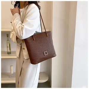 Detail of deep brown pleated tote bag featuring vertical accordion texture and square logo