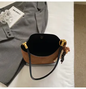 Detail of color-block bucket bag with wood bead charm and golden clasp closure