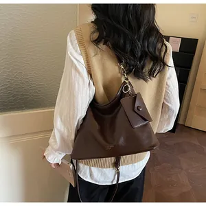Dettaglio della borsa tote marrone scuro con scritte dorate e pochette appesa