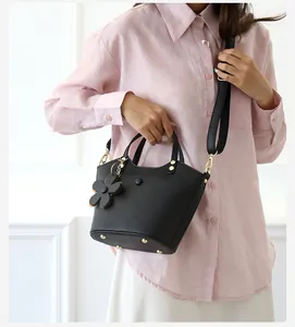 Close-up of black lychee grain bucket bag with gold hardware and floral charm details
