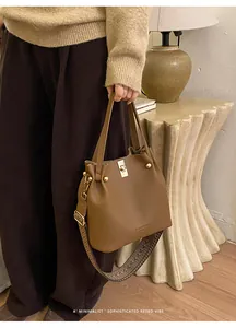 Detail of retro leather bucket bag with wide jacquard strap and gold swivel lock closure
