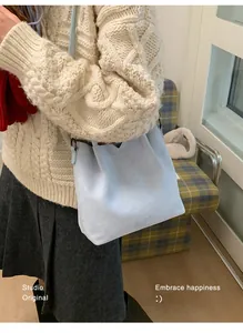 Détail du sac seau bleu clair en daim avec texture mate fine et bandoulière réglable