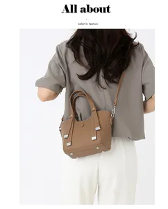 Détail d'un sac à main marron à grain litchi avec fermoir argenté et pieds de protection