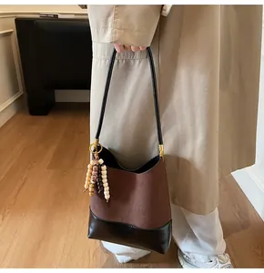 Close-up of retro brown suede and black leather patchwork bucket bag with bead tassel