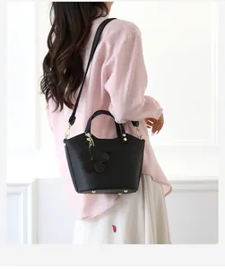 Black lychee leather bucket bag detail showing the flower charm and gold studs