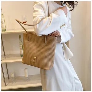 Model wearing a pleated shoulder tote bag with a square buckle in a modern home setting