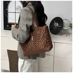 Detail einer Leopard-Print-Tasche mit braunen Ledergriffen und goldenem Metallschloss