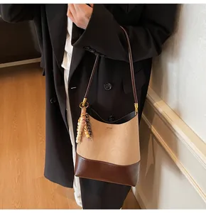 Detail of color-block bucket bag with matte khaki texture and dark brown leather base