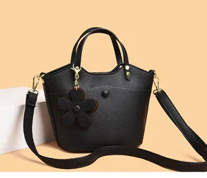 Detail of black litchi grain leather bucket bag with floral charm and gold hardware