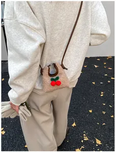 Detail einer Mini-Plüsch-Umhängetasche mit Kirschen, getragen von einem Model im Winter
