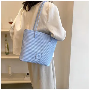 Detail of light blue pleated tote bag showing fine vertical stripes and shoulder strap