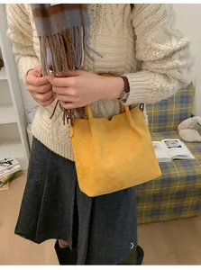 Détail du cabas en daim jaune vif porté avec un pull en maille blanc pour tenue hivernale