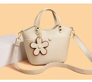 Detail of cream lychee texture handbag with flower charm and metallic hooks