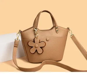 Detail shot of khaki bucket bag showing lychee pattern leather and floral charm
