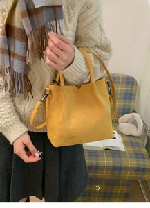 Gros plan du sac à main en daim jaune vif avec poignées et finitions gris foncé
