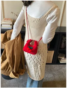 Detail einer roten Kirsch-Plüschtasche, getragen von einem Modell in gemütlicher Umgebung