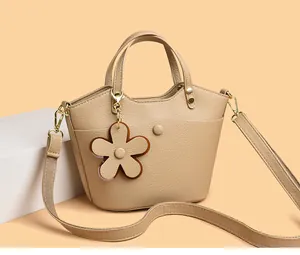 Close-up of beige lychee grain leather bucket bag with floral charm and gold hardware