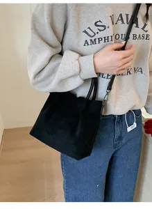 Mannequin portant un sac cabas en daim noir avec anses rondes et bandoulière réglable