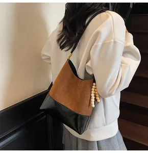 Detail of color-block tote bag with suede texture and wooden bead charm on handle