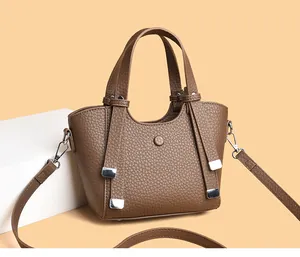 Détail du sac à main marron à motif litchi avec ferrures argentées et glands