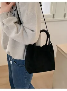 Gros plan sur le sac en daim noir montrant sa texture douce et ses poignées rondes