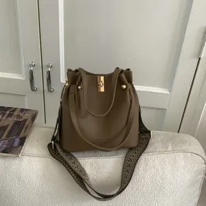 Brown lychee leather bucket bag with geometric strap and gold-tone turn-lock clasp
