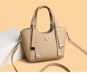 Détail macro du cuir grainé beige et des finitions métalliques argentées du sac