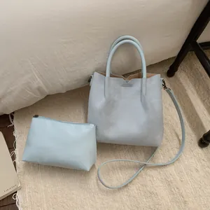 Détail d'un ensemble de sacs en daim bleu clair avec pochette assortie sur tapis