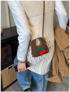 Detail einer braunen Plüsch-Mini-Umhängetasche mit handgefertigtem Kirsch-Häkeldesign