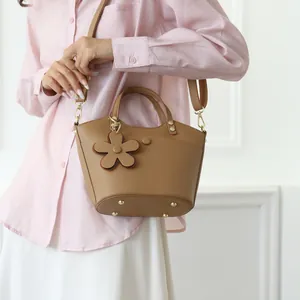 Brown leather bucket bag with flower charm and adjustable strap shown on model