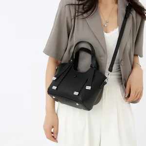 Sac à main minimaliste noir en cuir grainé avec détails argentés sur le mannequin