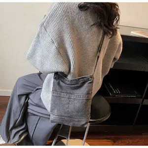 Vue détaillée du sac seau en denim gris foncé avec deux poches avant et bandoulière réglable