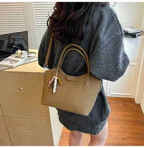 Detail der khakifarbenen Beuteltasche mit Holzperlenanhänger und verstellbarem Riemen