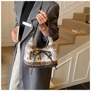 Dettaglio della borsa tote in peluche con fiocco in pelle marrone e morbido pile