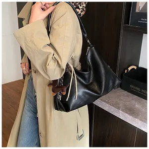 Détail d'un grand sac hobo noir en cuir souple orné d'un joli pendentif en forme de chien