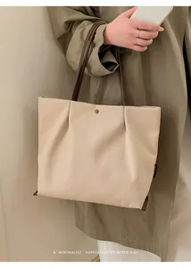 Detail of canvas tote bag showing brown leather handles and silver snap button closure
