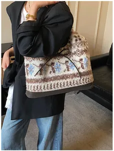 Dettaglio della borsa tote in peluche con motivi floreali e fiocco in pelle scura