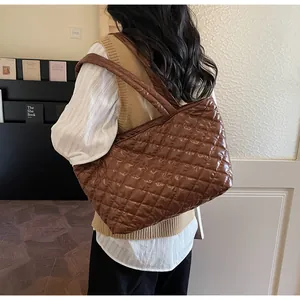 Detail of dark brown quilted tote bag showing padded strap and large capacity texture