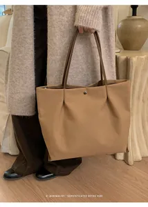 Detail of khaki tote bag showing smooth canvas texture and metallic snap closure