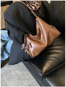 Détail d'un sac hobo en cuir marron avec structure plissée et accents latéraux tressés